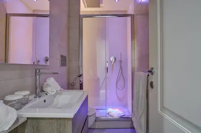 a bathroom with a sink and a shower with purple lighting at Spagna Boutique in Rome