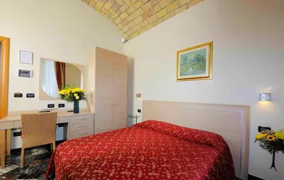 a bedroom with a red bed and a desk at Hotel Campidoglio in Rome