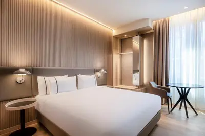 a hotel room with a large white bed and a table at AC Hotel by Marriott Clodio Roma in Rome
