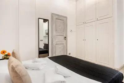 a white bedroom with a bed and a mirror at White flat Rione Monti in Rome