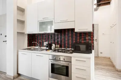 a white kitchen with a stove and a microwave at White flat Rione Monti in Rome
