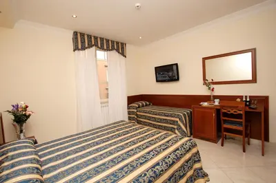 a bedroom with two beds and a desk and a mirror at Guest House Galaxy in Rome