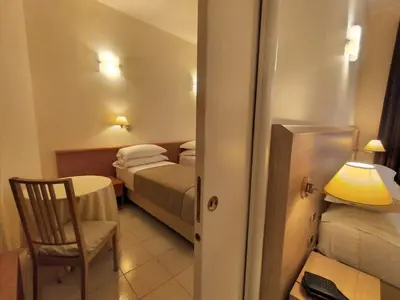 a hotel room with two beds and a table and a chair at Hotel Principe Eugenio in Rome