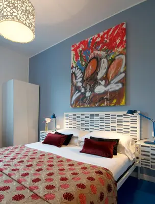 a bedroom with a large bed with a painting on the wall at B&B Amor in Rome