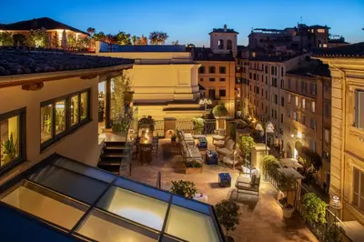 an apartment balcony with a patio in a city at night at 9Hotel Cesari in Rome