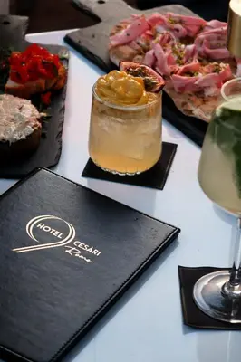 a table topped with plates of food and a drink at 9Hotel Cesari in Rome