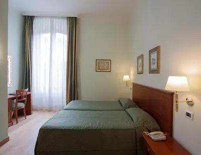 a bedroom with a bed and a desk and a window at Ateneo Garden Palace in Rome