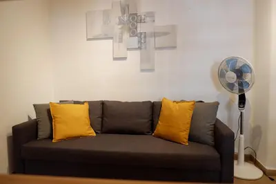 a couch with two yellow pillows and a fan at The Blue Strawberry House in San Giovanni Roma in Rome