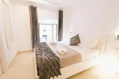 a white bedroom with a large bed with a window at San Pietro Grand Suite in Rome