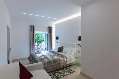 a white bedroom with a bed and a window at San Pietro Grand Suite in Rome