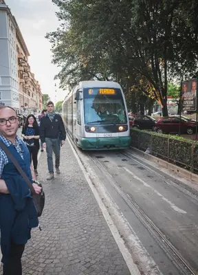 a train traveling down a street with people walking on the sidewalk at Guest House Vignola in Rome