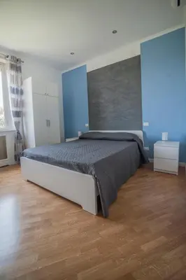 a bedroom with a large bed with blue walls and wooden floors at Guest House Vignola in Rome