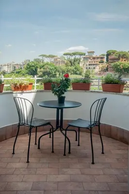 a table with two chairs and a flower pot on a balcony at Guest House Vignola in Rome