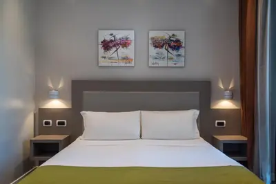 a bedroom with a bed with three paintings on the wall at Noba Hotel e Residenze in Rome