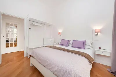 a white bedroom with a large bed with purple pillows at Lovatelli Home al Campidoglio in Rome
