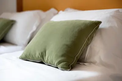 a green pillow on a bed with white pillows at HT Residence Maximus in Rome
