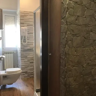 a bathroom with a toilet and a stone wall at Appartamento S.Giovanni in Rome