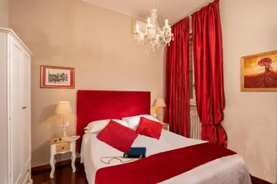 a bedroom with a red and white bed and a chandelier at Avignonesi Suites - CA Domus Collection in Rome
