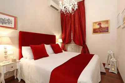 a bedroom with a red and white bed and a chandelier at Avignonesi Suites - CA Domus Collection in Rome