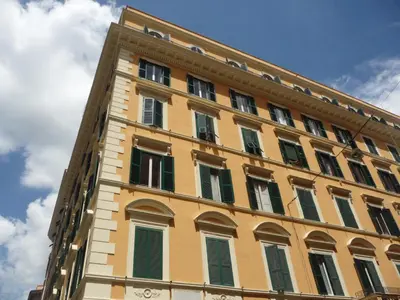 a tall yellow building with green shuttered windows at Nice Rome Holiday in Rome