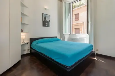 a bed in a room with a large window at GuestHost - Palazzo Borghese Lovely Flat in Rome