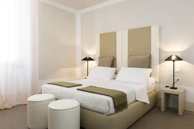a white bedroom with a large bed with two stools at Relais Santa Maria Maggiore in Rome