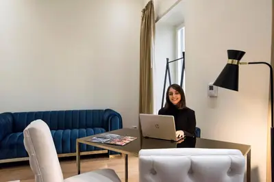 a woman sitting at a table with a laptop at Amazing Piazza Venezia Suites in Rome