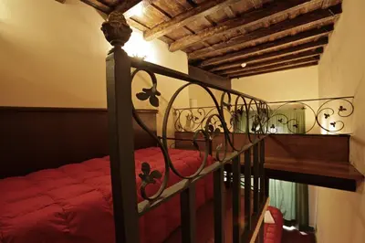 a bedroom with a bed with red sheets and a wooden staircase at Hotel Panda in Rome