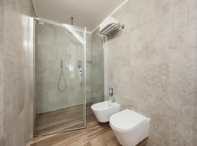 a bathroom with a toilet and a glass shower at Hotel Flavia in Rome