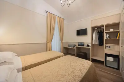 a hotel room with two beds and a tv at Hotel Flavia in Rome