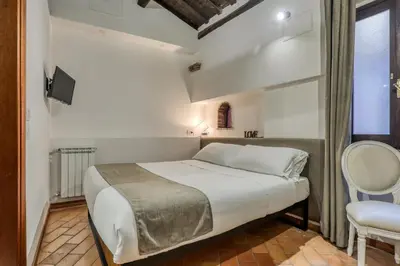a bedroom with a bed and a chair and a window at Easybnb - Luxury Navona in Rome