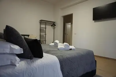 a bedroom with two beds with towels and a flat screen tv at VMH Vatican Modern House in Rome