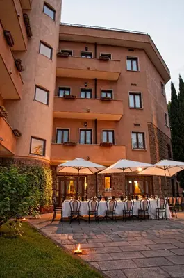 a group of tables with umbrellas in front of a building at Hotel Cilicia in Rome