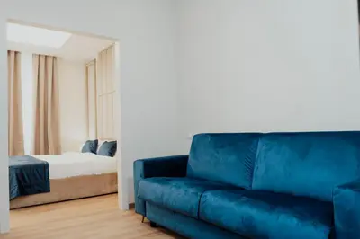 a living room with a blue couch and a bed at Cesare ai Cavalieri Suites in Rome