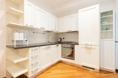 a white kitchen with white cabinets and a wooden floor at Borgo Vittorio St. Peter Apartments in Rome