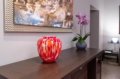 a red vase sitting on top of a wooden table with a vase at Harry's Bar Trevi Luxury Apartments - Modelli in Rome