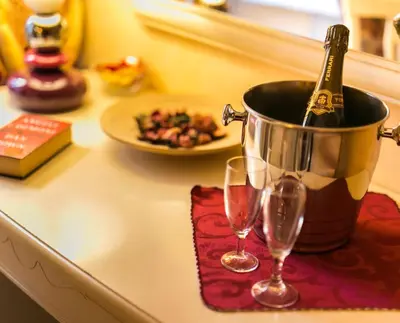 a bottle of champagne in a bucket on a counter with two glasses at Hotel Erdarelli in Rome