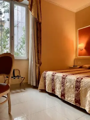 a bedroom with a bed and a window and a chair at Hotel Erdarelli in Rome