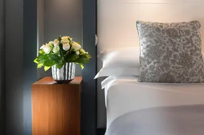 a vase of flowers on a table next to a bed at Hotel Metropolis in Rome