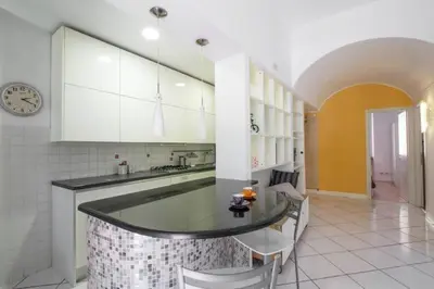 a kitchen with a counter with chairs and a clock at Trastevere St. Garden House in Rome