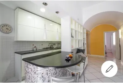 a kitchen with a counter with chairs and a clock at Trastevere St. Garden House in Rome
