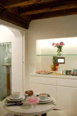 a room with a table with plates and flowers on it at Gigli D'Oro Suite in Rome