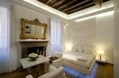 a white bedroom with a bed and a fireplace at Gigli D'Oro Suite in Rome
