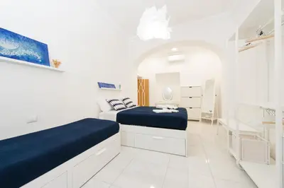 a white bedroom with two beds and a bathroom at Ottaviano Exclusive Maison in Rome