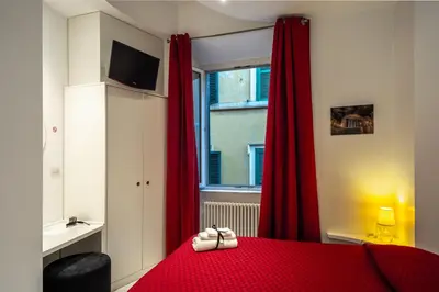 a bedroom with a red bed with red curtains and a window at Intra' Residenza in Trastevere in Rome
