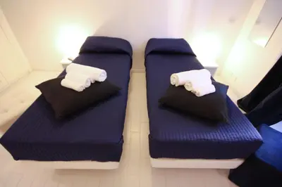 two beds in a room with blue and white pillows at Intra' Residenza in Trastevere in Rome