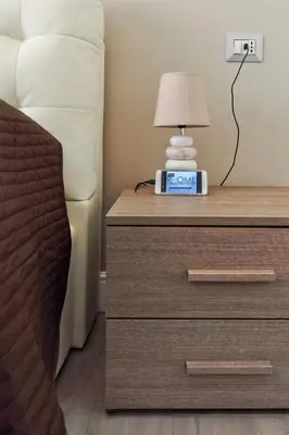 a bedside table with a lamp on top of a dresser at Pianeta roma 48 in Rome