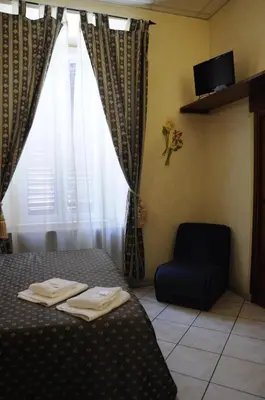 a bedroom with a bed and a chair and a window at Hotel Farini in Rome