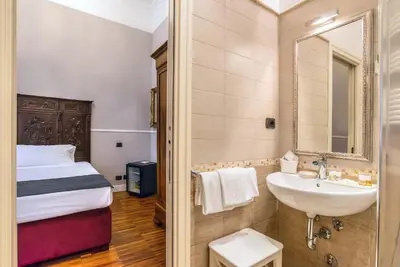 a bathroom with a sink and a bed and a mirror at I TRE MOSCHETTIERI - D'ARTAGNAN Luxury Guest House in Rome