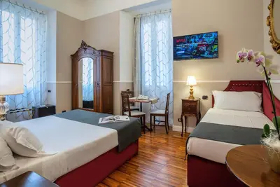 a hotel room with two beds and a table at I TRE MOSCHETTIERI - D'ARTAGNAN Luxury Guest House in Rome